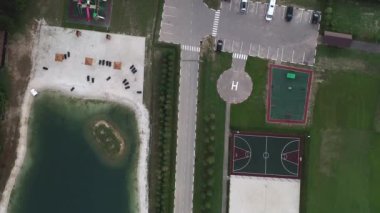 A view from above at the cottage village recreation areas, road, parking, lake, sports grounds: tennis, volleyball, basketball, football and a workout area in the countryside