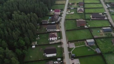 A view from above at the cottage village areas and infrastructure, roads, houses, dense forest and the countryside landscape on the warm summer day