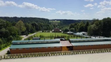 A view from above at the cottage village recreation areas, road, sports grounds: open arena for horses on the hot summer day in the countryside, horse ride in the nature, horseback riding