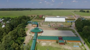 A view from above at the cottage village recreation areas, road, sports grounds: open arena for horses on the hot summer day in the countryside, horse ride in the nature, horseback riding