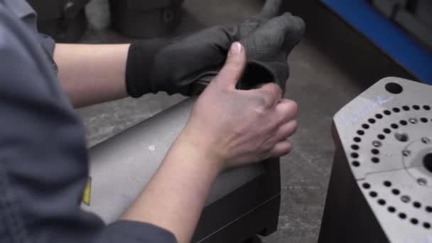 Працівник кладе рукавички на руки для роботи з виготовленими деталями - перевірки якості та відповідності стандартам, крупним планом на виробничому процесі на заводі — стокове відео