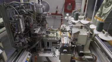 Kumaş ve giysi fabrikasındaki otomatik eklenti tezgahına yakın çekim, giysi fabrikasında çalışma günü, kumaş üretimi