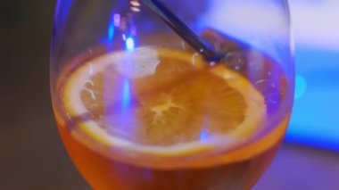 Soğuk içeceğin yanına bir parça portakal ve siyah bir tüple yakın. Bir konserde, partide, müzik partisinde, neon ışıklarda.