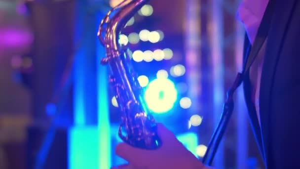 Een blanke man speelt saxofoon op een concert, feest, muziekfeest, neon kleuren, saxofoon spelen close-up, muziek maken en improvizen op het feest, windband — Stockvideo