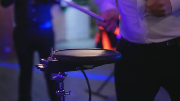 Um homem caucasiano toca bateria em um concerto, festa, festa de música, cores de néon, tocando bateria de perto, fazendo música e improvisando na festa, percussionista — Vídeo de Stock