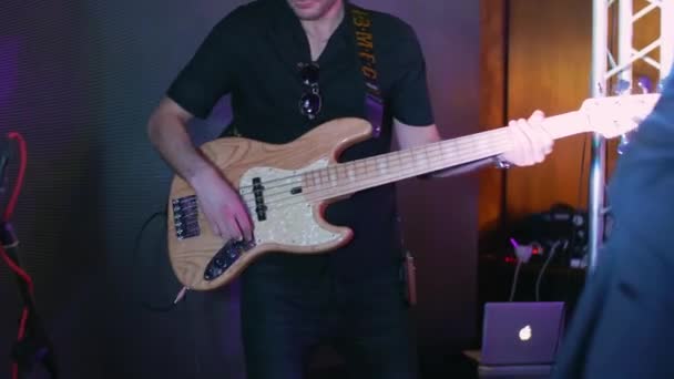 Een blanke man speelt elektrische basgitaar op een concert, feestje, muziekfeest, neon kleuren, basgitaar solo close-up — Stockvideo