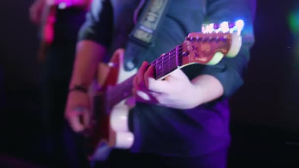 Seorang pria Kaukasia memainkan gitar listrik di sebuah konser, pesta, pesta musik, warna neon, rhythm guitar solo close up — Stok Video