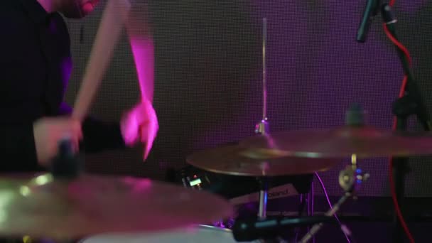 En kaukasisk man spelar trummor på en konsert, fest, musikfest, neonfärger, spelar trummor på nära håll, gör musik och improviserar på festen, slagverkare — Stockvideo