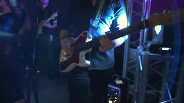 Ένας Καυκάσιος παίζει ηλεκτρική κιθάρα σε μια συναυλία, πάρτι, μουσικό πάρτι, νέον χρώματα, ρυθμική κιθάρα σόλο από κοντά — Αρχείο Βίντεο