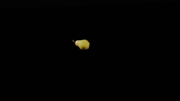 Close-up em maduro pêra amarela voa para cima e girando em um fundo preto em câmera lenta tiro, exibição de frutas vívidas, pêra voadora — Vídeo de Stock
