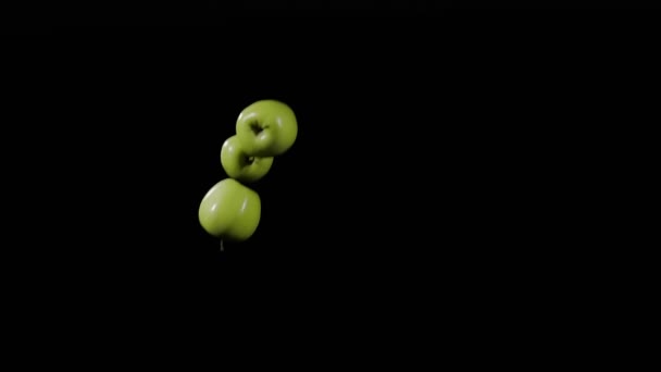 Nahaufnahme der Gruppe von drei Äpfeln fliegen auf und drehen sich auf schwarzem Hintergrund in Zeitlupe, lebendige Obstdarstellung, fliegende grüne Äpfel — Stockvideo
