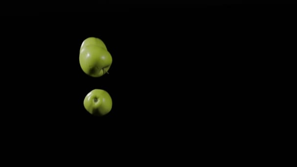 Nahaufnahme der Gruppe von drei grünen Äpfeln fliegen auf und drehen sich auf schwarzem Hintergrund in Zeitlupe, lebendige Obstdarstellung — Stockvideo