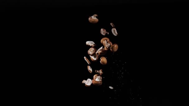 Os champinhons picados frescos molhados voam e giram com salpicos de água em um fundo preto em tiro em câmera lenta, gotas de água em cogumelos — Vídeo de Stock