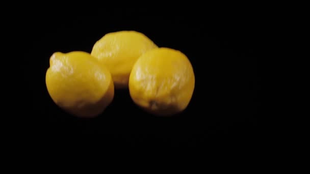 세 개의 신선 한 레몬의 그룹에 근접하게 날아 느린 모션 샷에서 검은 배경에서 회전 — 비디오