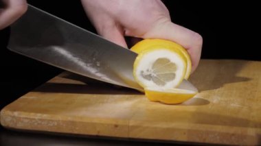 Erkekler siyah arka planda tahtayı keserken limonu bıçakla keserler.