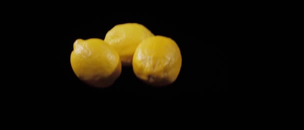 Sekelompok tiga lemon segar dilempar ke atas dan terbang di sekitar pada latar belakang hitam dalam gerak lambat — Stok Video
