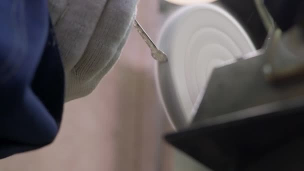 Een arbeider poetst de afgewerkte zilveren lepel met een gereedschapswerktuig in de fabriek voor de productie van zilveren voorwerpen — Stockvideo