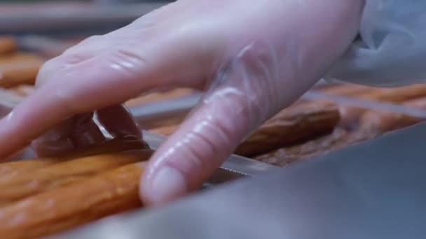 Close-up nas mãos dos trabalhadores colocando salsichas prontas em embalagens de plástico — Vídeo de Stock