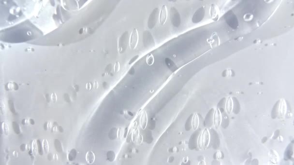 Прозрачная косметическая гелевая жидкость стекает по белой поверхности. Макро Шот — стоковое видео