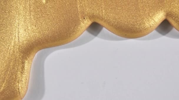 Fluido gel oro con scorrimento verso il basso su una superficie bianca. Oro fuso. Sovrapposizione del flusso di vernice liquido giallo scintillante. Macro Shot — Video Stock
