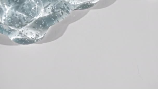 Líquido de gel transparente con burbujas que fluyen hacia abajo sobre una superficie blanca. Macro Shot — Vídeo de stock