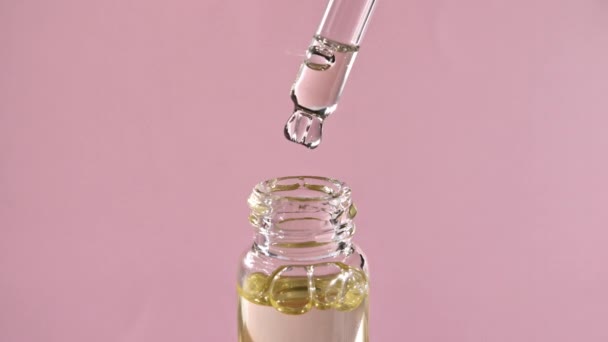 Крапля падає з піпетки в медичній пляшці крупним планом, ізольована на рожевому фоні — стокове відео