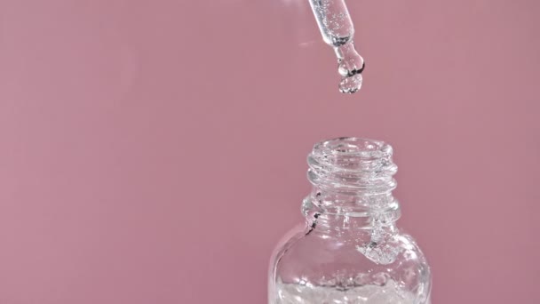 Drop falls from a pipette in a medical bottle close-up, isolated on a pink background — Stock Video