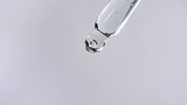Gri zemin üzerinde yağ damlaları olan kozmetik pipeti