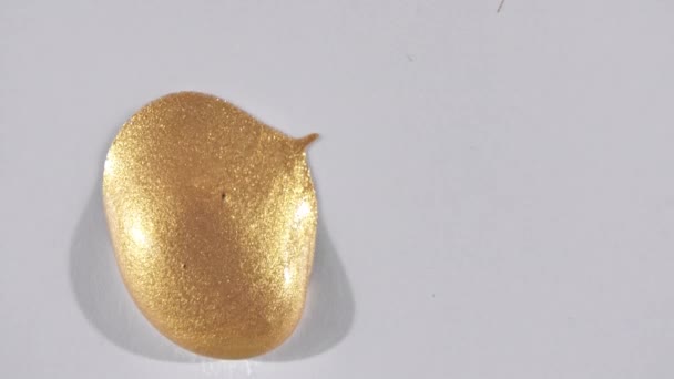 Χρυσό τζελ υγρό με ροή κάτω σε μια λευκή επιφάνεια. Λιωμένος χρυσός. Επικάλυψη ροής αφρώδους κίτρινου υγρού χρώματος. Μακρο-βολή — Αρχείο Βίντεο