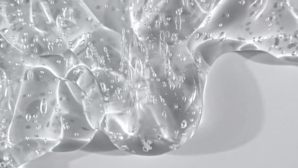 Líquido cosmético transparente del gel que fluye abajo en una superficie blanca. Macro Shot — Vídeo de stock