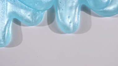 Beyaz bir yüzeyde mikro baloncuklu mavi sıvı jel kremi. Makro Vuruş