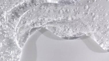 Beyaz bir yüzeye dökülen şeffaf kozmetik jel sıvısı. Makro Vuruş