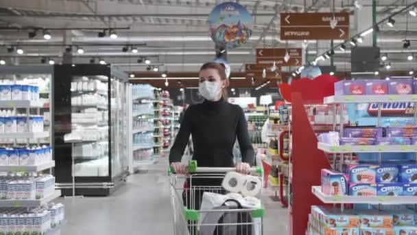 보안경을 쓰고 있는 여성이 코로나 바이러스가 유행하는 동안 슈퍼마켓에서 음식을 선택 한다. 검역중 안전 한 쇼핑 , COVID-19 코로나 바이러스 대유행. — 비디오