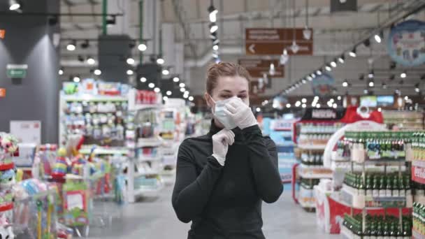 Une jeune femme séduisante portant un masque de protection dans le magasin. Processus de mise femelle sur le visage masque.Mouvement lent — Video