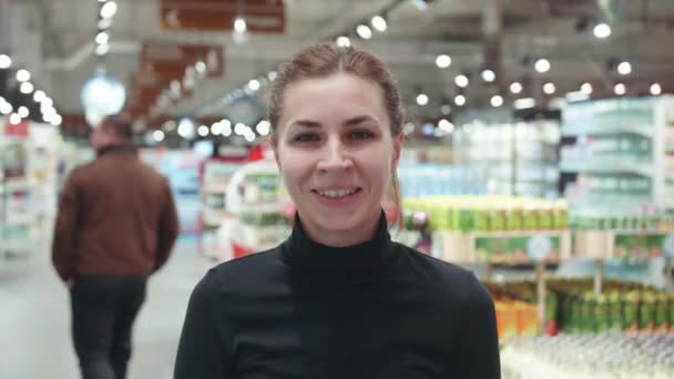 Mujer hermosa y joven sonriendo en una tienda — Vídeo de stock