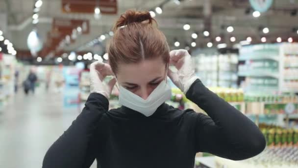 En ung attraktiv kvinna som bär en skyddande mask i butiken. Process för kvinnor att ta på sig ansiktsmask. — Stockvideo
