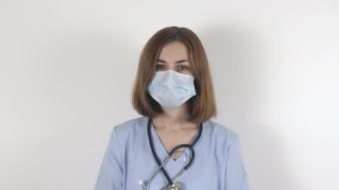 Genç bayan doktor maskeyi çıkarıyor. Kırmızı bölgede vardiya sonrası hemşire..