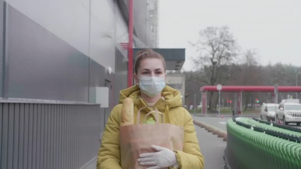 Молодая женщина с покупками в супермаркете. Женщина в маске с покупками в магазине. — стоковое видео