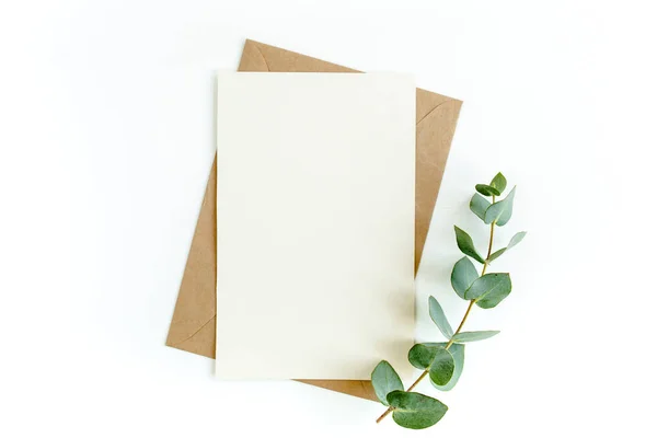 Макет запрошення, чиста вітальна листівка і зелене листя евкаліпта. Плоский прошарок, вид зверху . — стокове фото