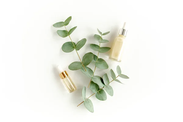Aceite esencial de eucalipto, hojas de eucalipto sobre fondo blanco. Productos cosméticos naturales y orgánicos. Medicinal, sueros naturales. Piso tendido, vista superior. — Foto de Stock