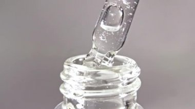 Gri zemin üzerinde yağ damlaları olan kozmetik pipeti