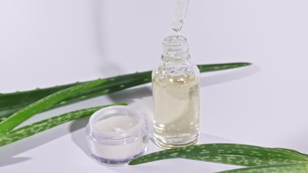 Tropferglasflasche mit Aloe Vera Öl. Kosmetika auf Basis von Aloe Vera-Extrakt. Weißes Glas mit Gesichtscreme. Haut- und Körperpflege auf weißem Hintergrund. — Stockvideo