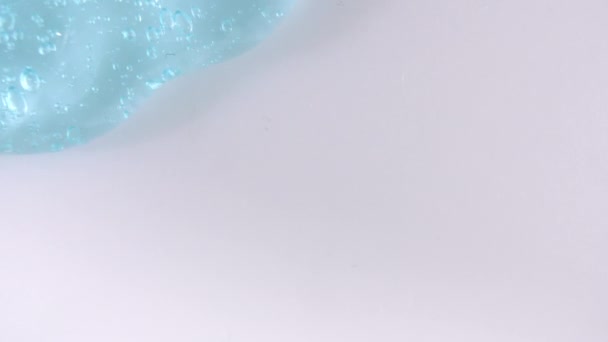Líquido de gel azul transparente con burbujas que fluyen hacia abajo sobre una superficie blanca. Macro Shot — Vídeos de Stock