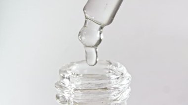 Gri zemin üzerinde yağ damlaları olan kozmetik pipeti