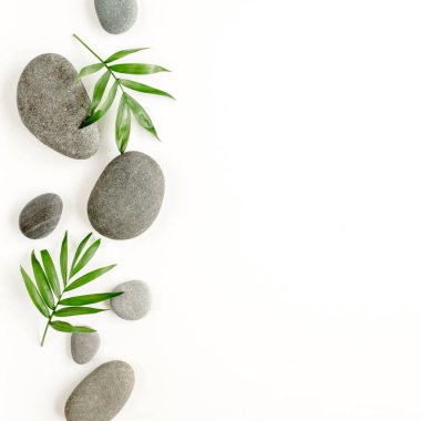 Spa taşları, palmiye yaprakları, mum ve zen beyaz arka plandaki gri taşlar gibi. Düz yatış, üst görünüm