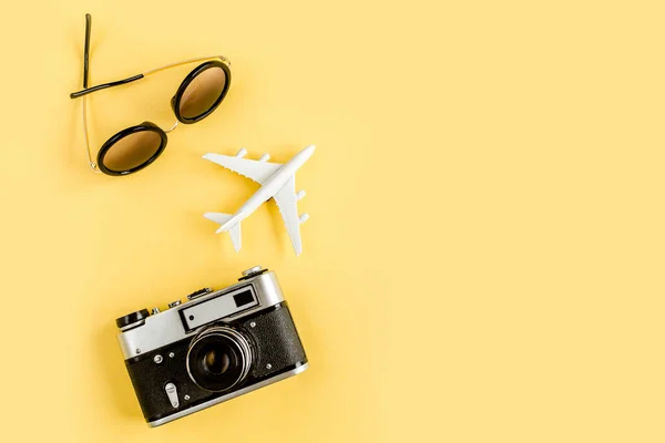 Conceito de acessórios para viajantes em fundo amarelo. Câmera retrô, avião modelo, avião e folha de palma tropical. — Fotografia de Stock