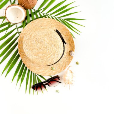 Gezgin aksesuarları, tropikal palmiye yaprağı dalları, beyaz arka planda hasır şapka ve metin için boş alan. Seyahat tatili kavramı. 