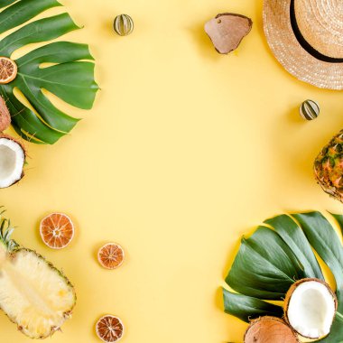 Tropikal çerçeve, arka planda egzotik meyveler ve sarı arka planda tropikal palmiye yaprakları. Düz yatış, üst görünüm