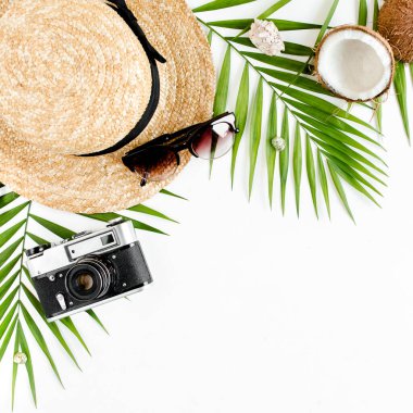 Gezgin aksesuarları, tropikal palmiye yaprağı dalları, beyaz arka planda hasır şapka ve metin için boş alan. Seyahat tatili kavramı. 