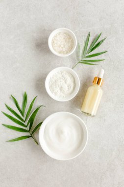 Kadın derisi ve vücut bakımı kozmetik ürünleri seti: yüz kremi, kozmetik kil, deniz tuzu, gri mermer arka planda hyaluronik bir şişe.. 